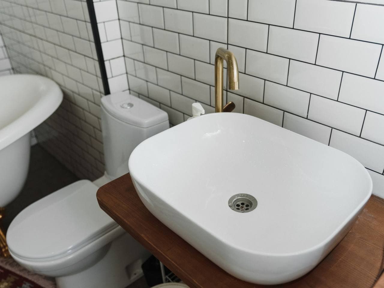 Bílé keramické umyvadlo na desce a WC v koupelně s bílým obkladem